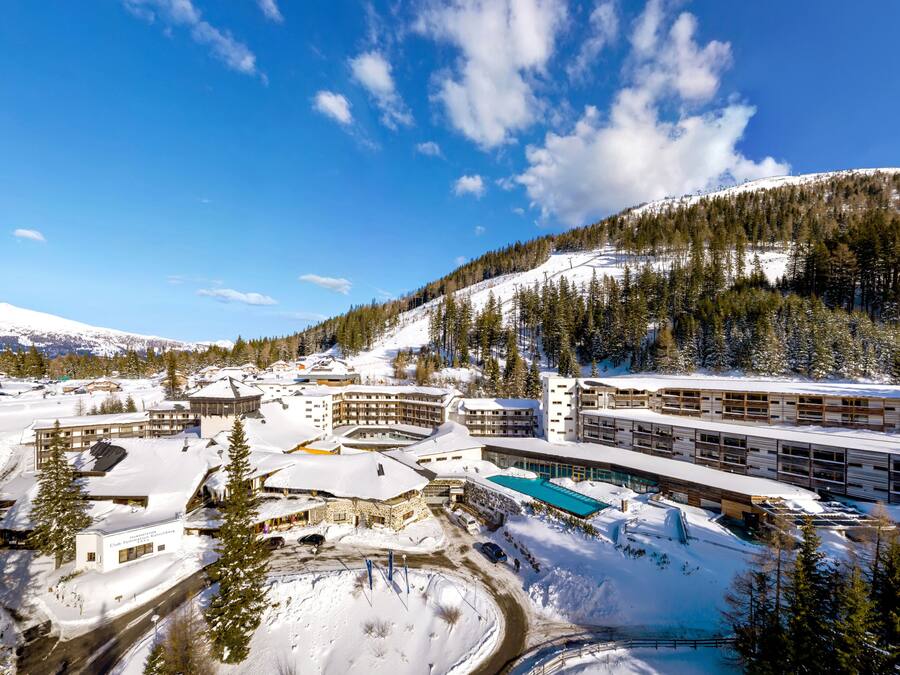 A snow-covered resort with multiple buildings, a pool area, and a ski slope.