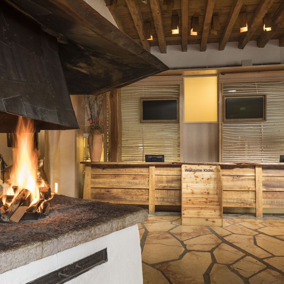 A stone-floored kitchen with a wood-burning stove, wooden cabinets, and a welcome sign.