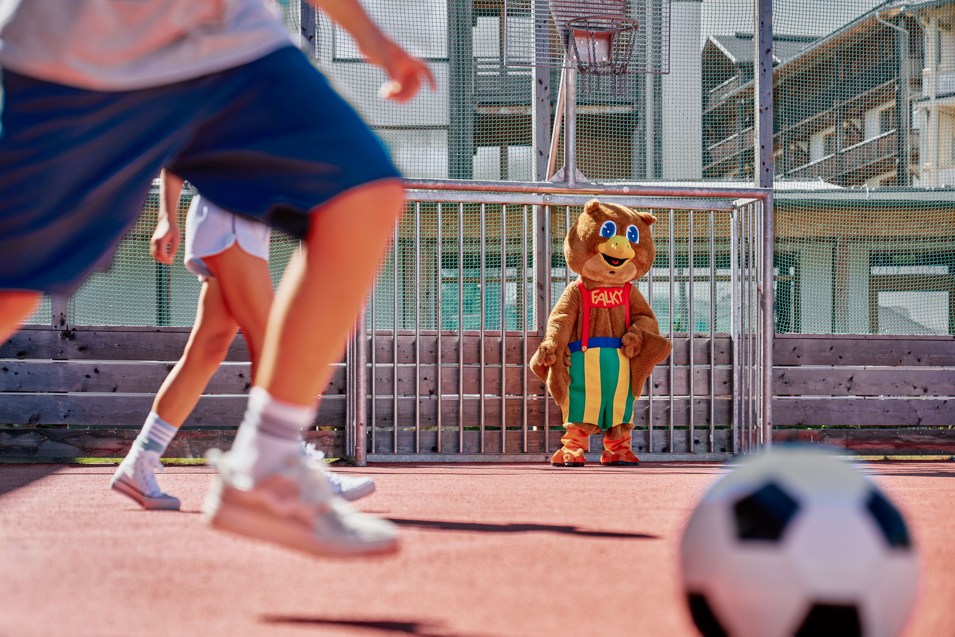 A mascot in a sports uniform standing in front of a goalpost.