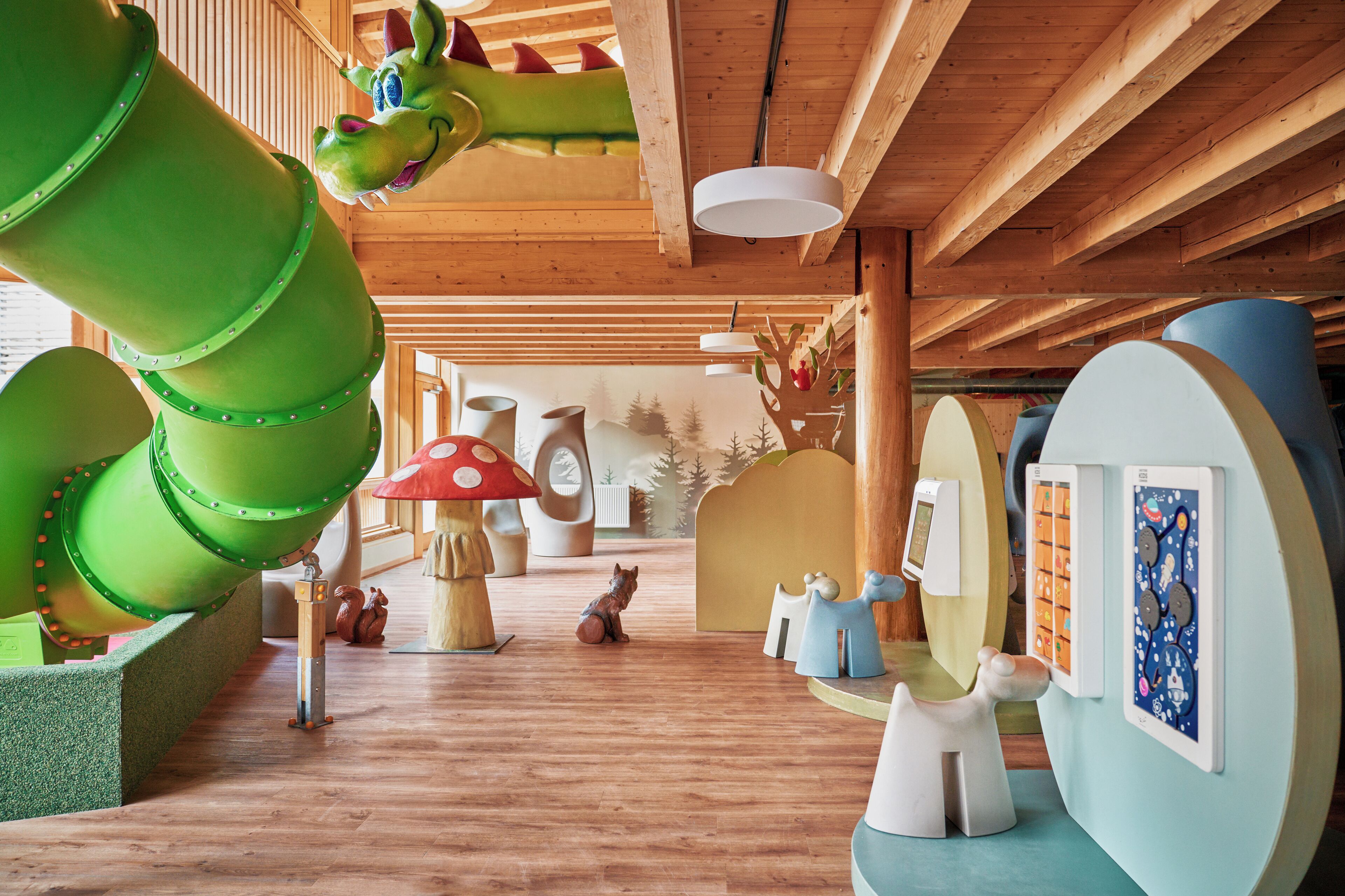A play area with a green slide, a large mushroom sculpture, and various play structures.