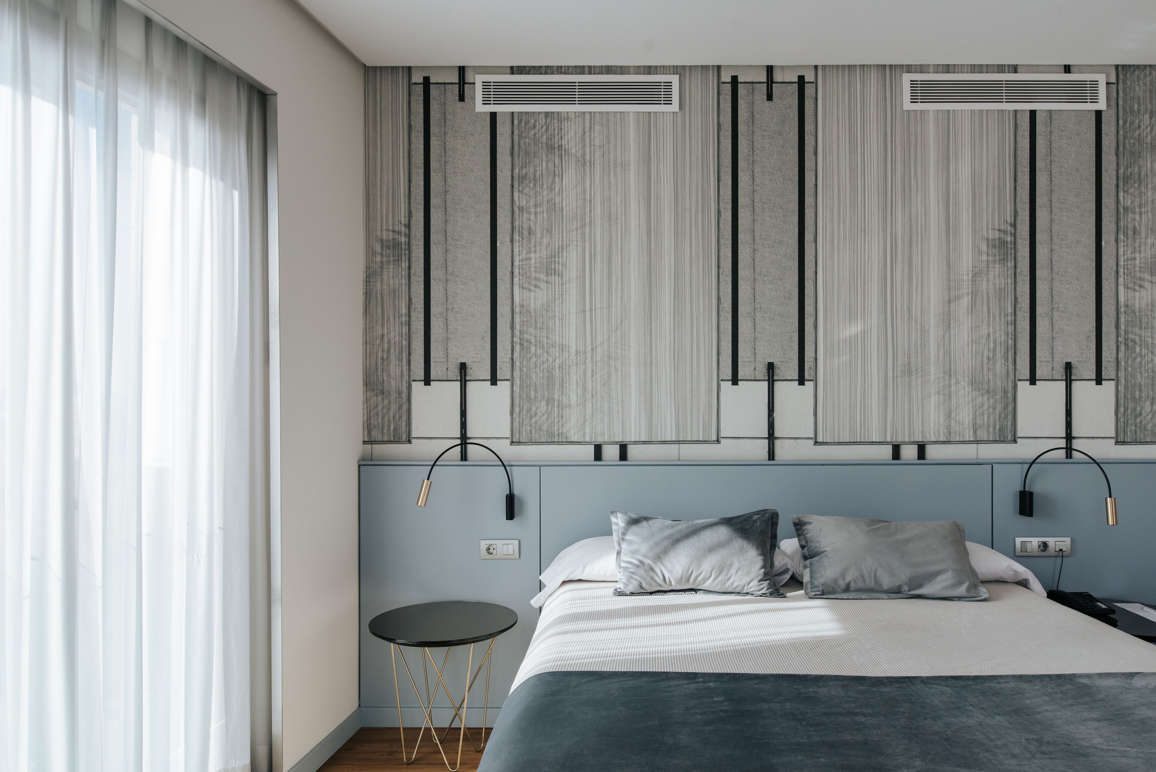 Une chambre moderne avec un lit, deux tables de chevet et une grande fenêtre avec des rideaux.