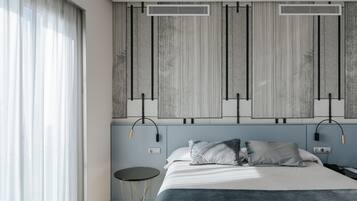 A modern bedroom with a bed, two bedside tables, and a large window with curtains.