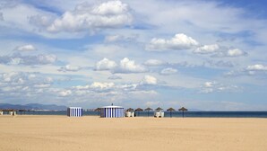 A beach with striped beach huts and thatched umbrellas. - Hotel Neptuno Playa & Spa (Valencia)