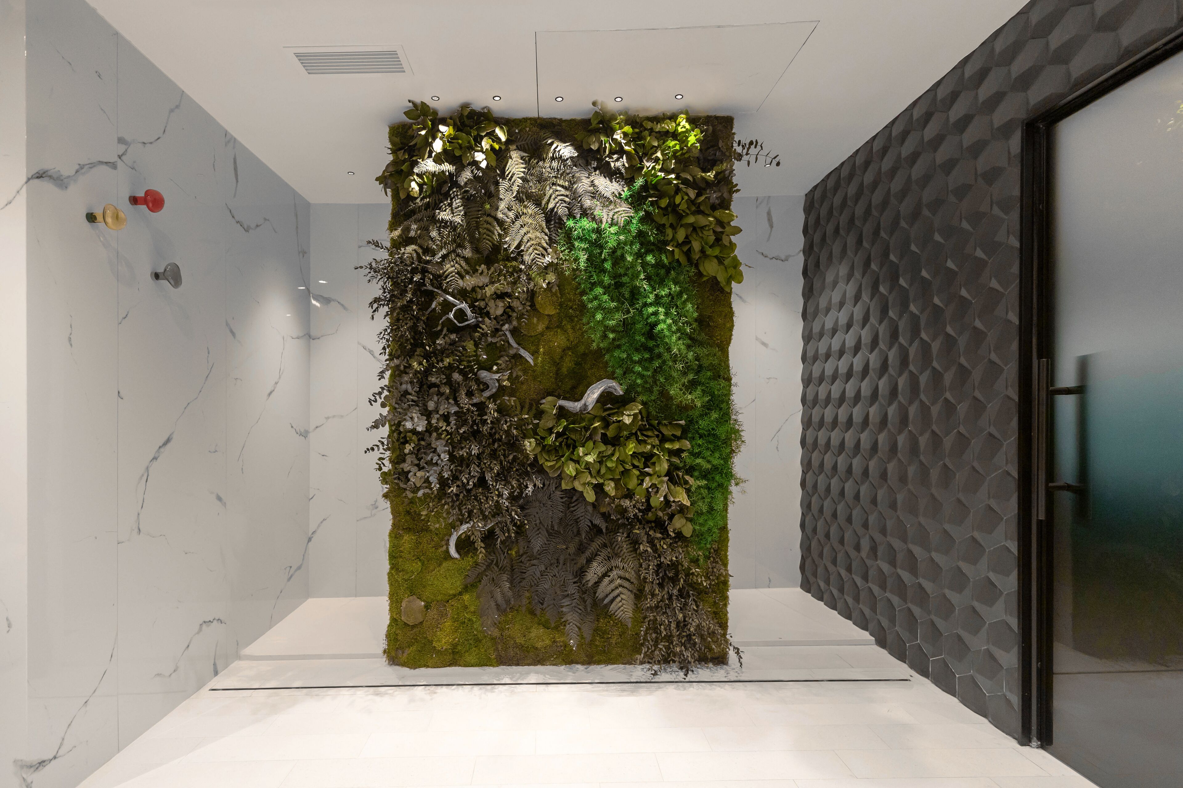 A modern interior with a vertical garden wall, a geometric patterned wall, and a white floor.