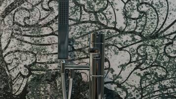 Un baño moderno con una llave metálica elegante y un cabezal de ducha de mano.