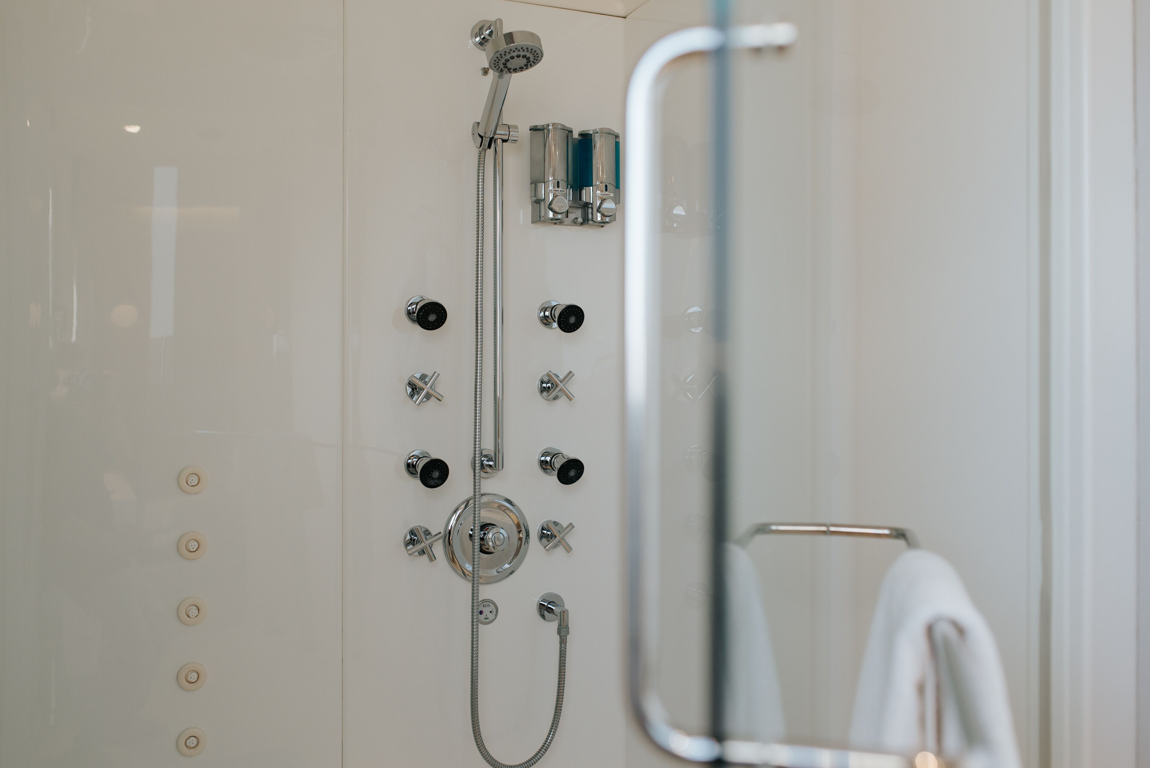 A modern shower with multiple controls and a handheld showerhead.