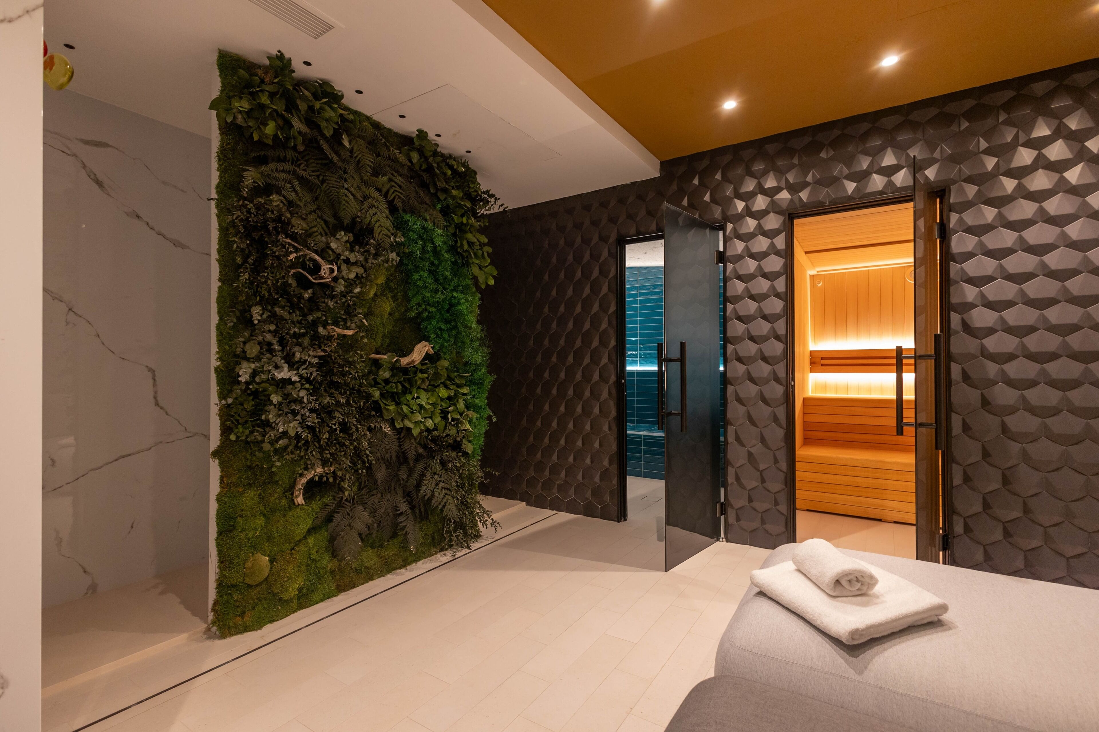 Un moderno vestíbulo de hotel con una pared verde, un panel con diseño geométrico y una puerta de madera que da a una habitación.