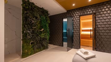 Un moderno vestíbulo de hotel con una pared verde, un panel con diseño geométrico y una puerta de madera que da a una habitación.