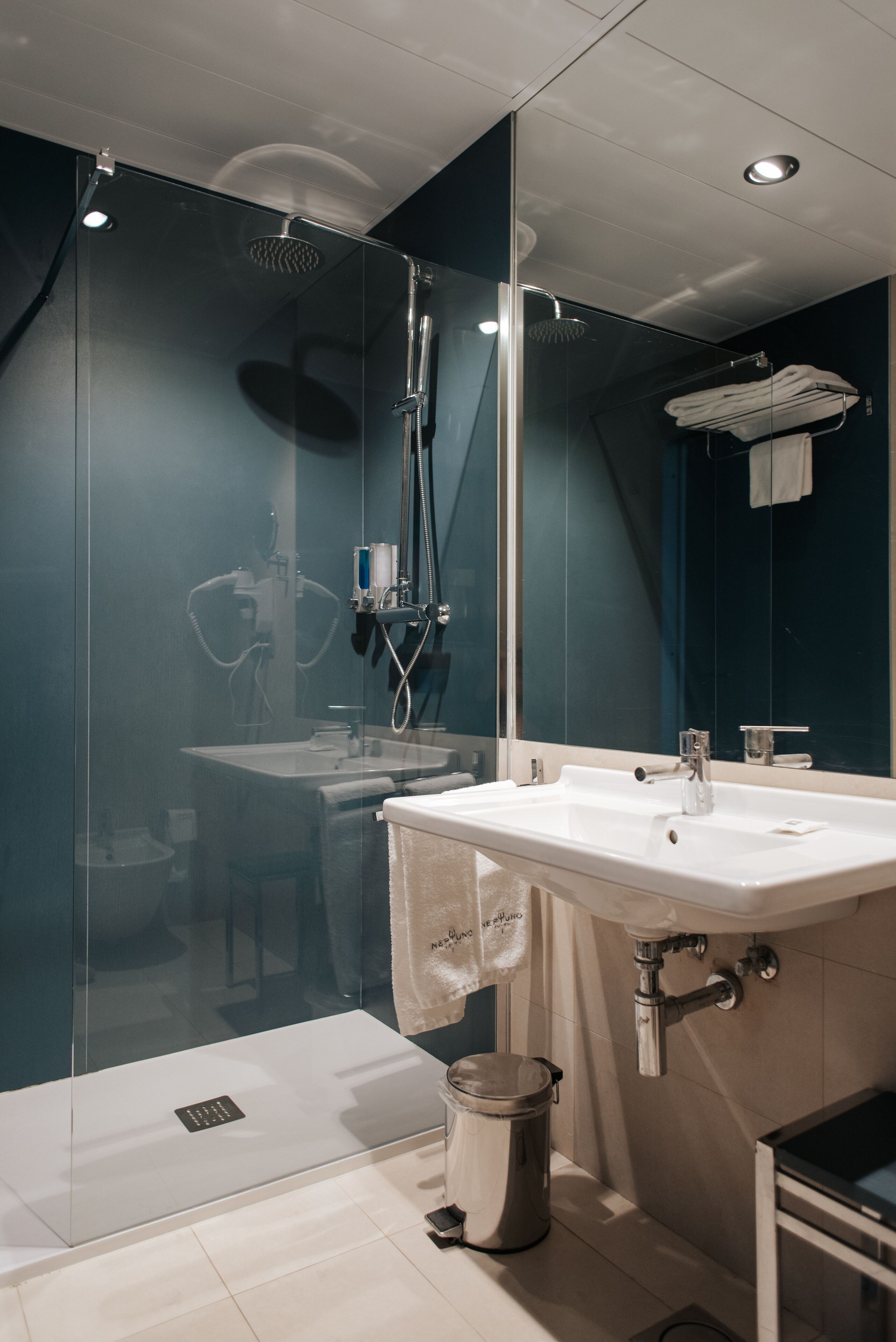 Een moderne badkamer met een douchecabine van glas, een wit wastafelmeubel en een handdoekrek.