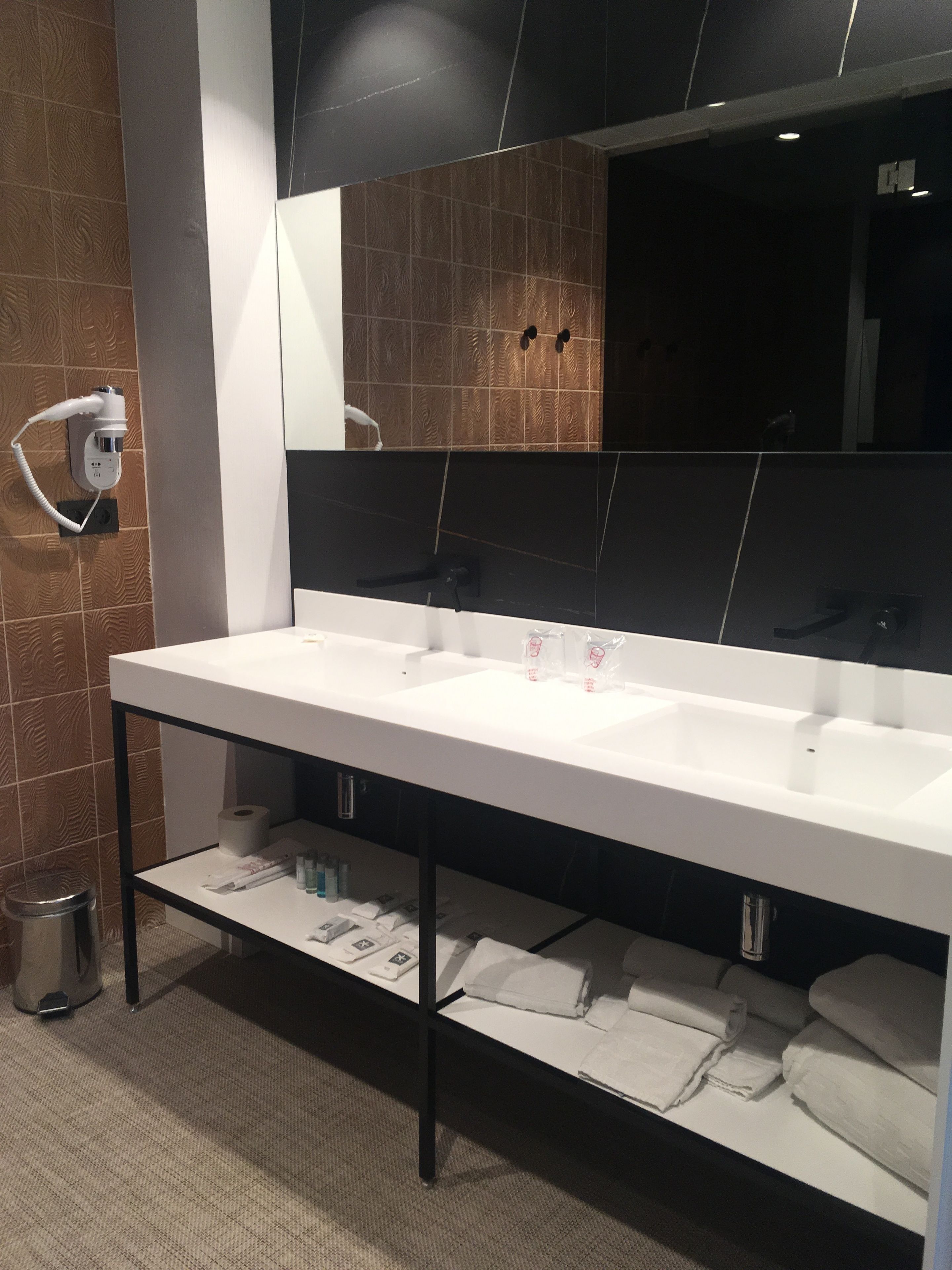 A modern bathroom with two sinks, a large mirror, and a towel rack.