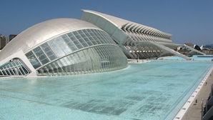 Ein modernes Gebäude mit einer großen, gebogenen Glasfassade und einem Pool im Vordergrund.