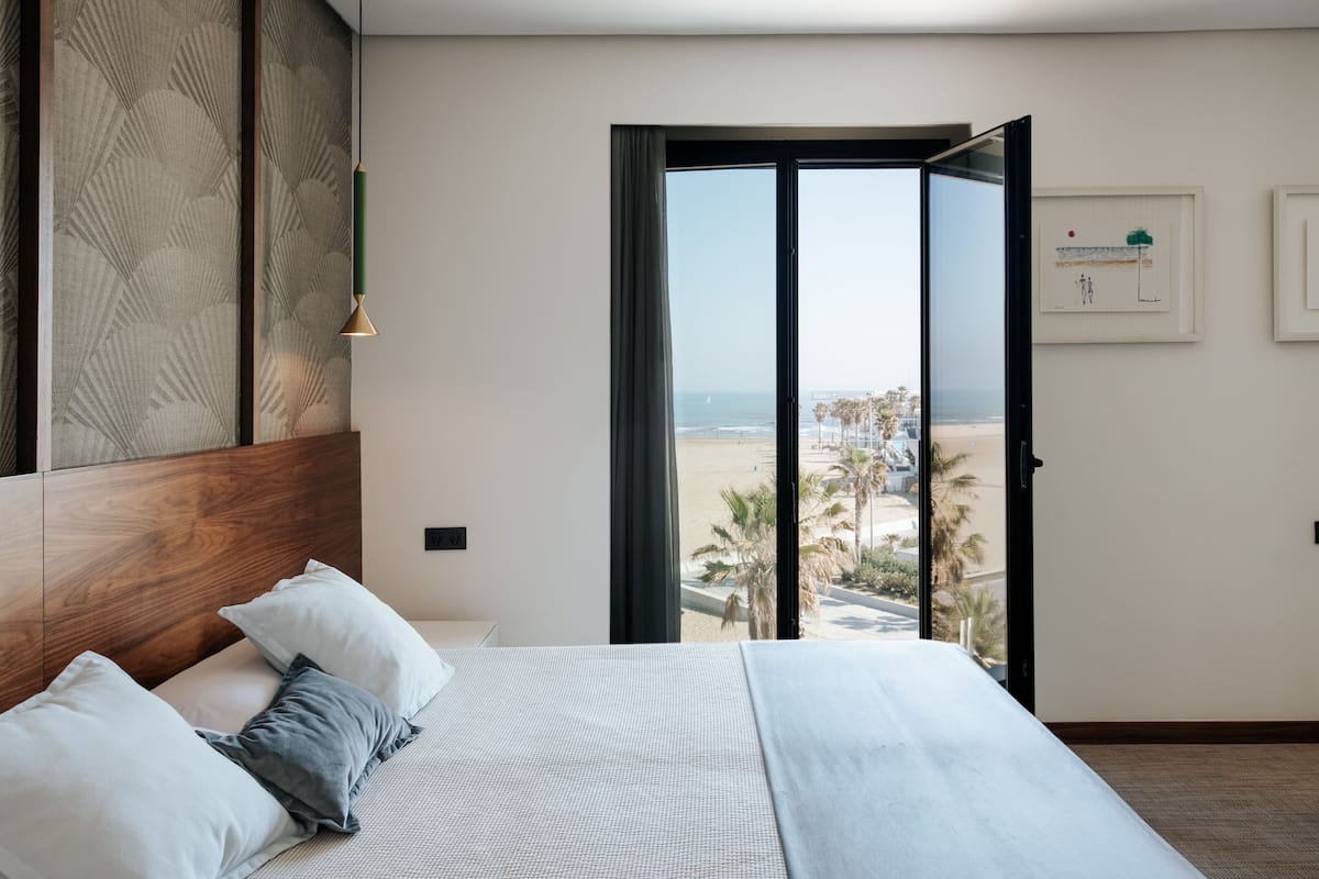 Un dormitorio con una cama grande, vistas a la playa y una puerta corredera al exterior.