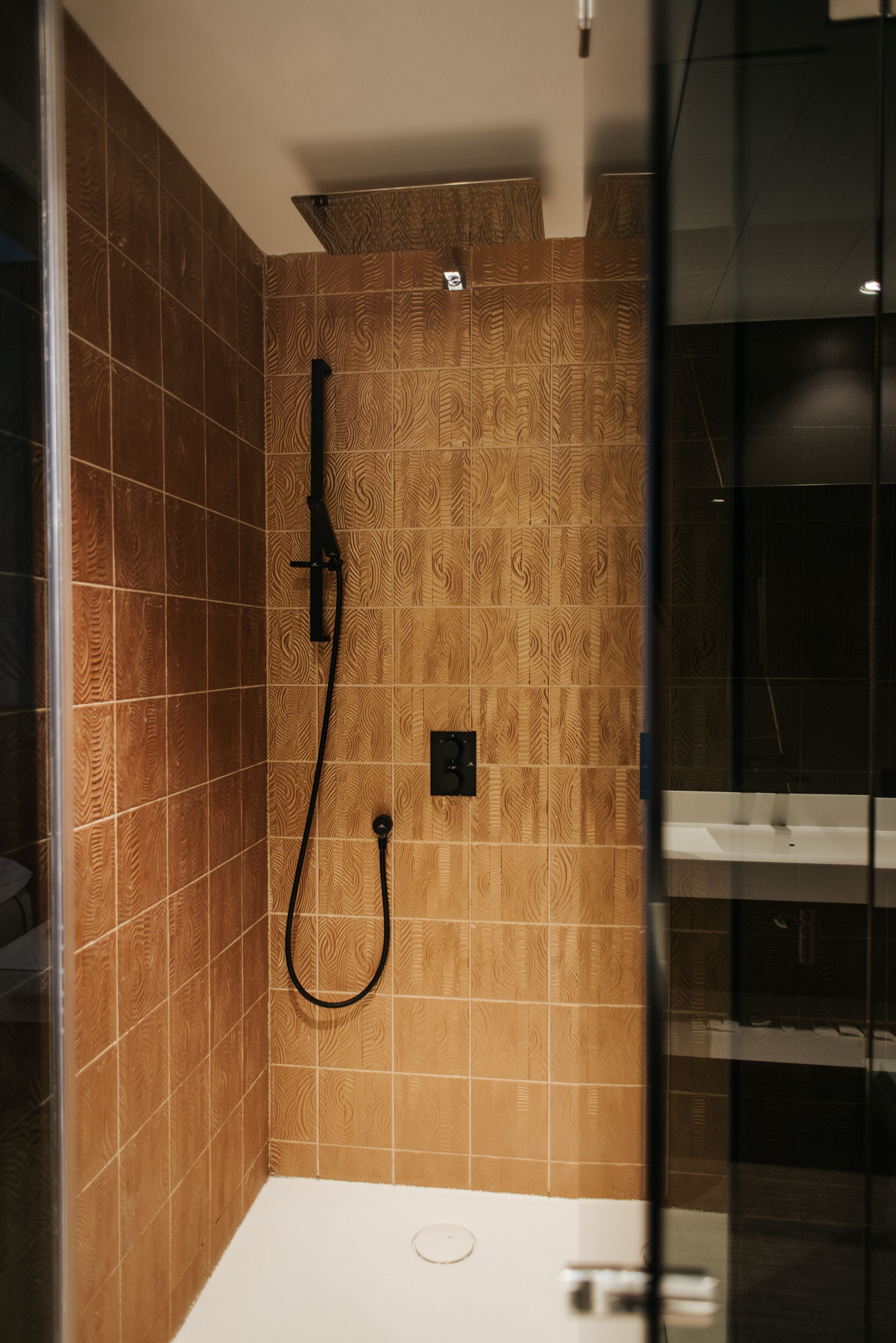A modern bathroom with a shower area, tiled walls, and a glass partition.