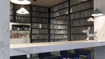Zona de bar moderna con encimera de mármol, taburetes azules y lámparas colgantes.