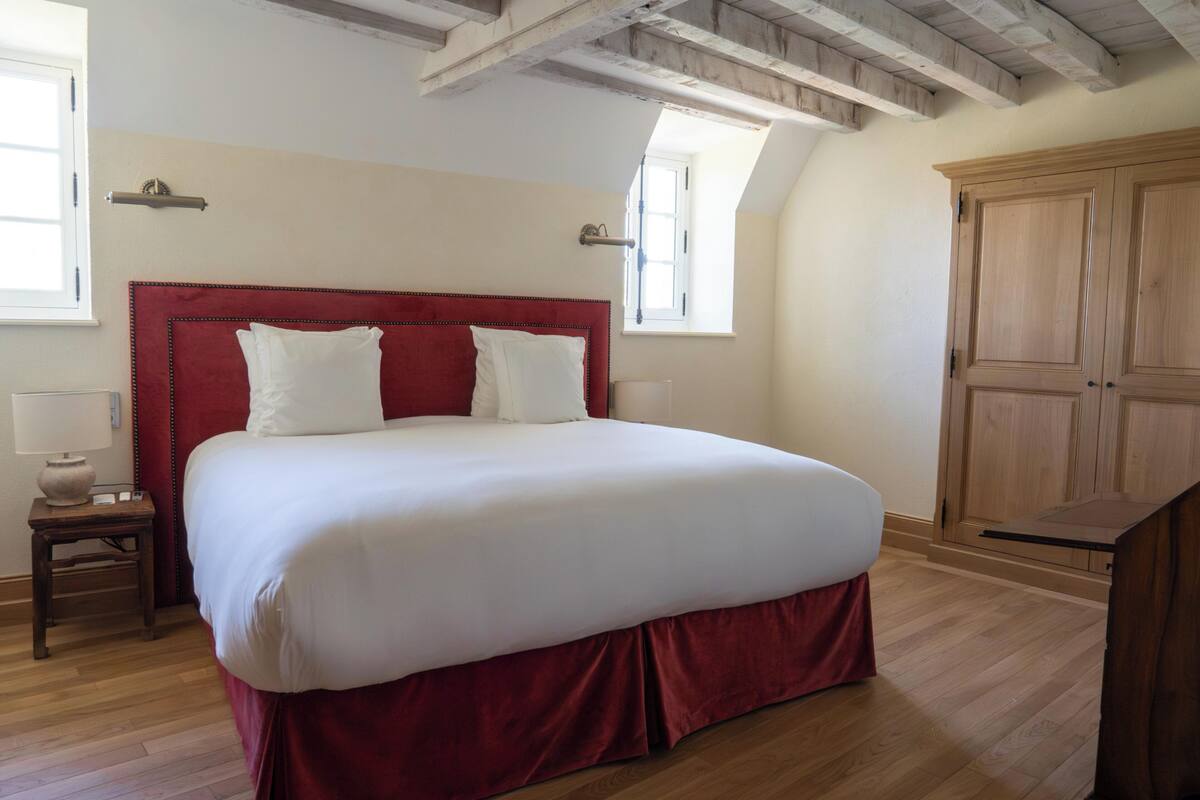 Ein Schlafzimmer mit einem großen Bett, Holzboden, einem Kleiderschrank und einem Fenster.