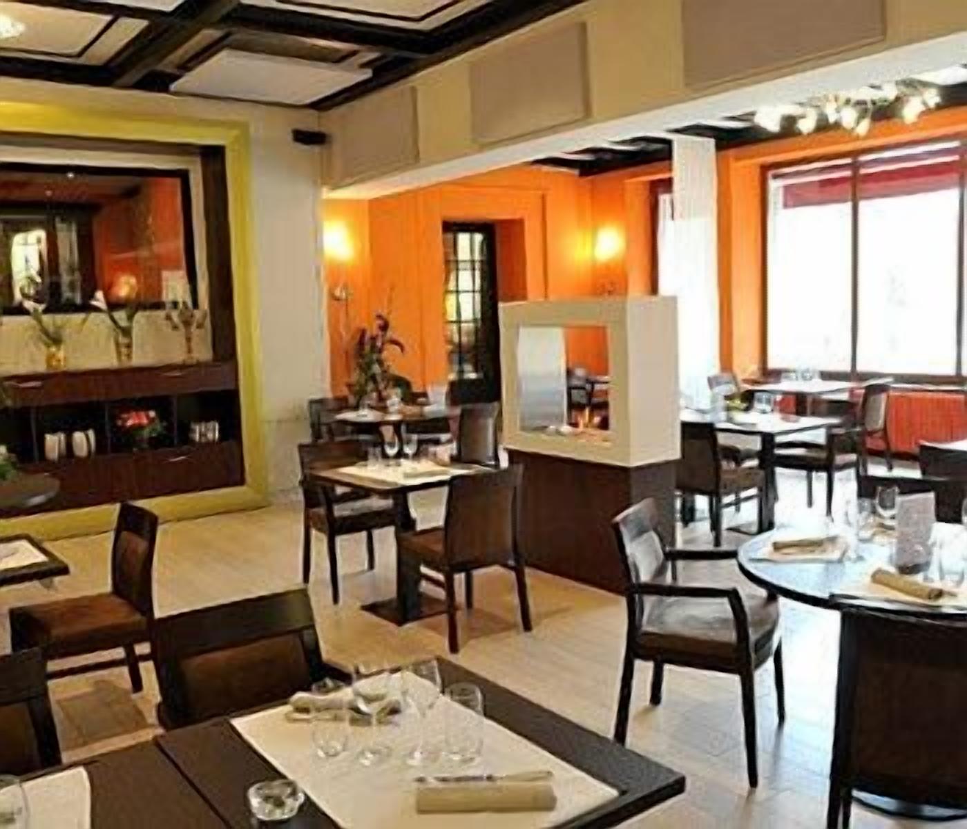 Un restaurant doté de nombreuses tables et chaises, d’un bar et offrant une vue sur le paysage urbain grâce à de grandes fenêtres.