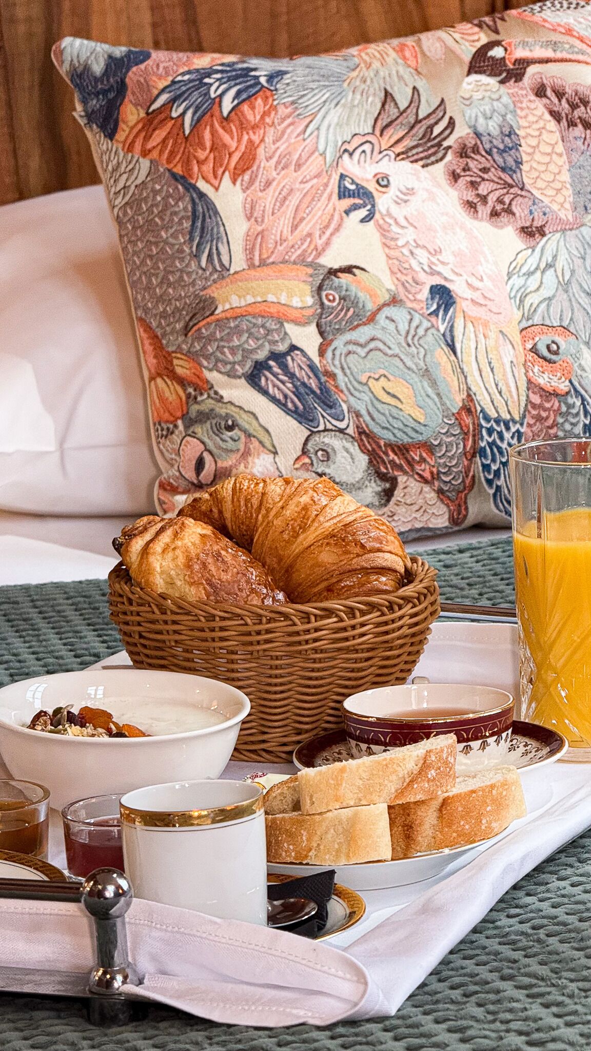 Un plateau de petit-déjeuner avec des croissants, du yaourt, du pain et un verre de jus d’orange.