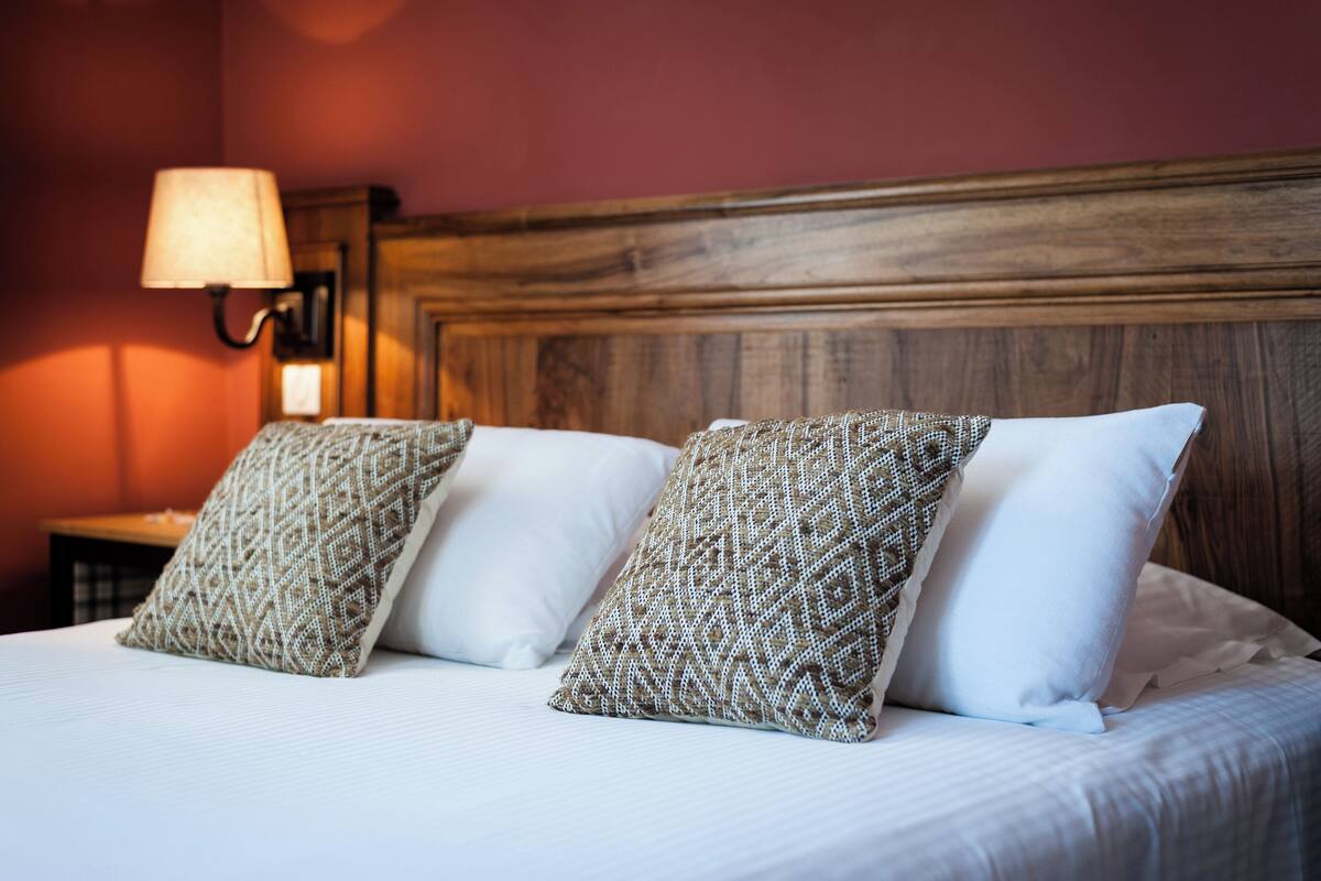 A bed with patterned pillows, a wooden headboard, and a nightstand with a lamp.