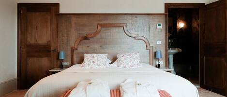 A neatly made bed with a wooden headboard, two pillows, and a bedside table with a lamp.