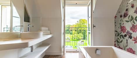 A modern bathroom with a large window, a bathtub, and a sink.