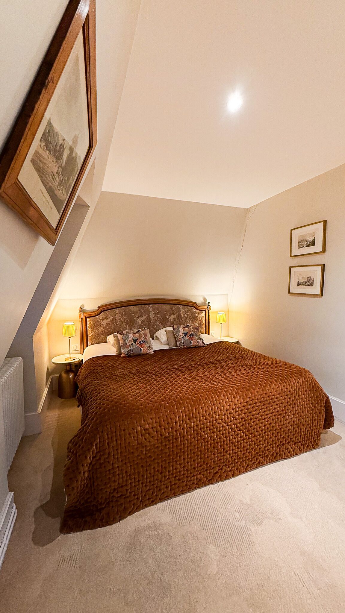 A bedroom with a large bed, two bedside lamps, and a framed picture on the wall.