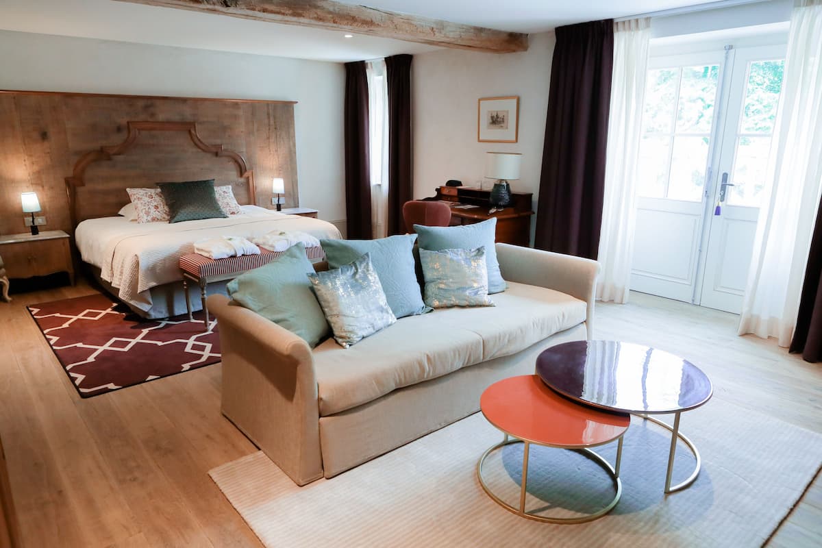 A bedroom with a bed, a sofa, a small table, and a desk with a chair.