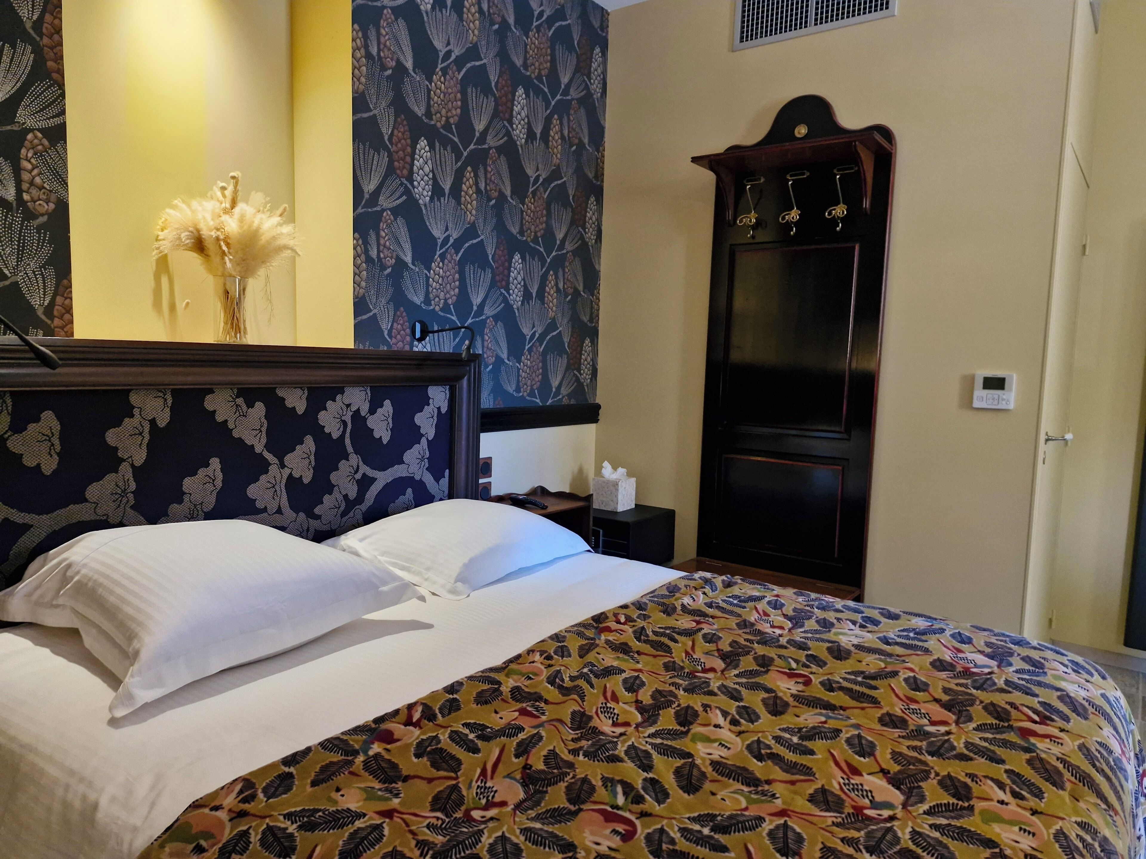 A hotel room with a bed, a nightstand, a dresser, and a wall-mounted heater.