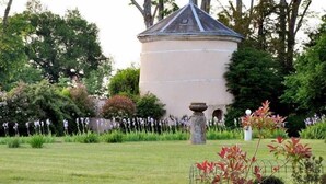 A garden with a round building, a stone well, and various plants. - Domaine de Moresville (Flacey)
