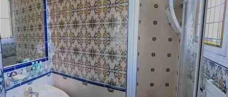 A bathroom with patterned tiles, a sink, and a shower area.