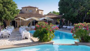 Zona de piscina con mobiliario exterior y un edificio de piedra al fondo.