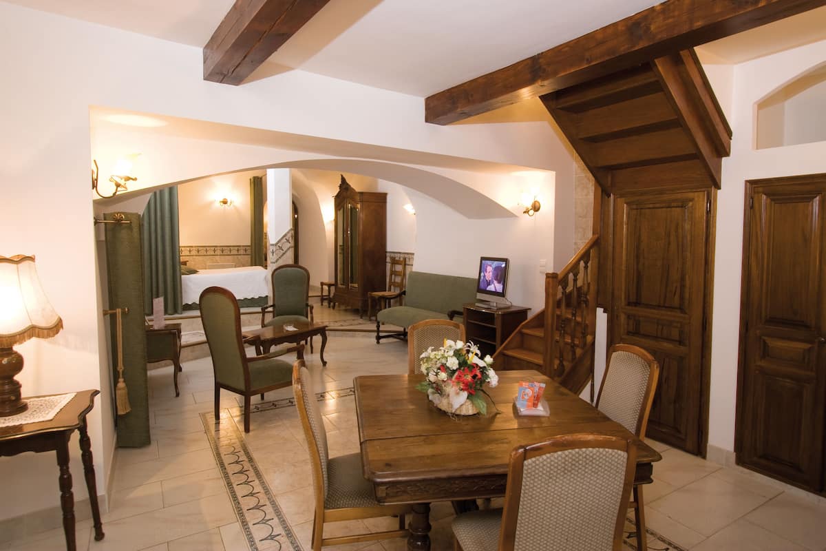 A dining area with a wooden table, chairs, and a television. There is a staircase leading to another room.