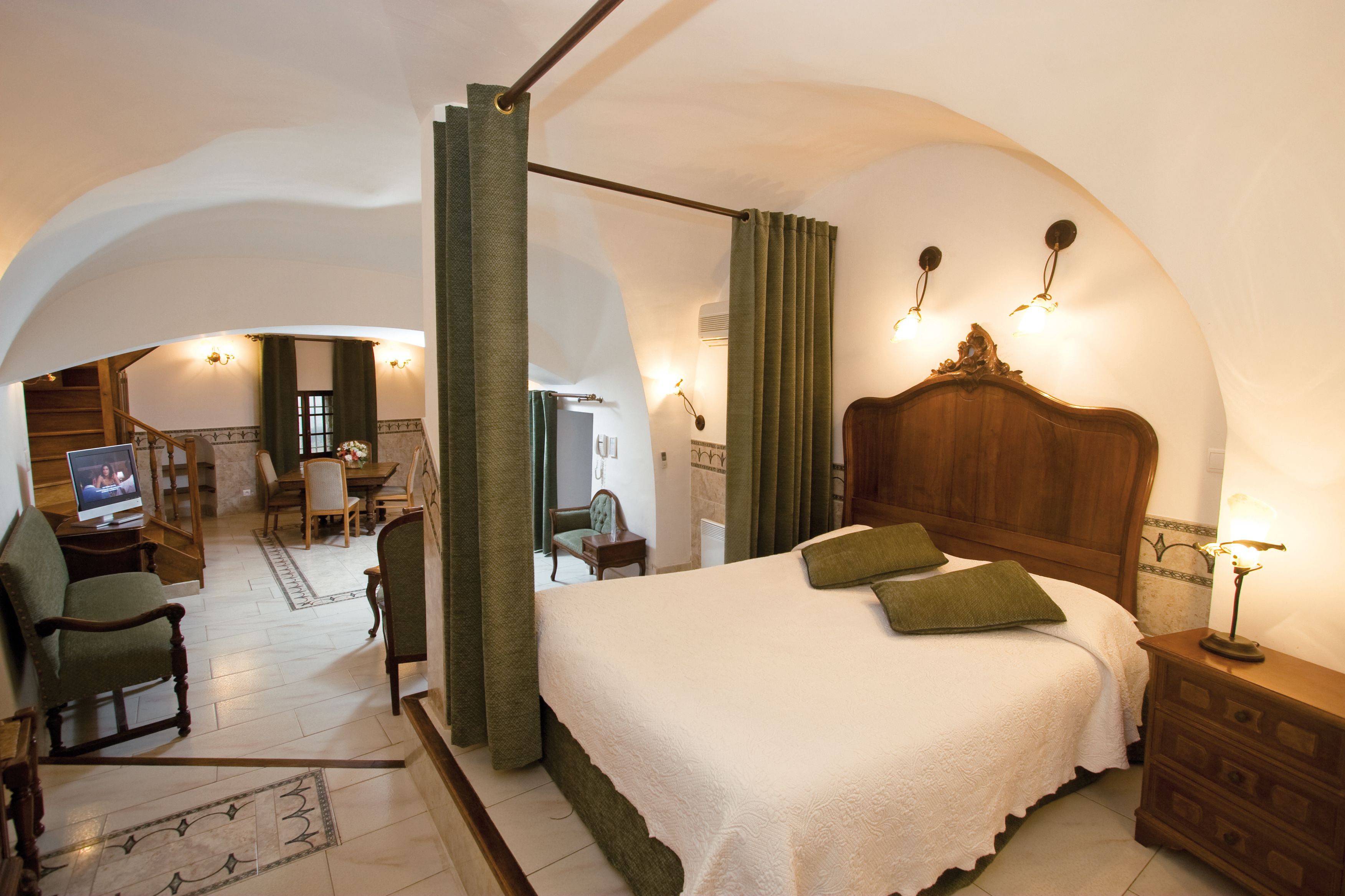 Une chambre spacieuse avec un grand lit, une table de chevet en bois et un téléviseur placé dans un coin.