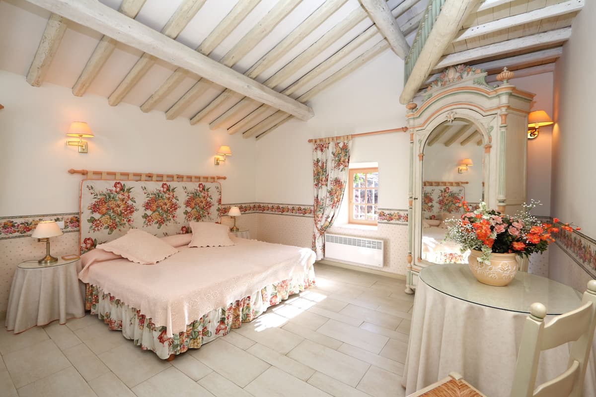 A bedroom with a bed, a dresser, a mirror, and a window with curtains.