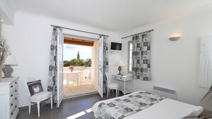 Un dormitorio con cama, escritorio, silla y televisor.