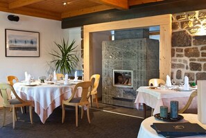 A dining area with two tables set for a meal, a stone fireplace, and a framed picture on the wall.