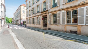 A street with buildings, including a hotel with shutters and balconies. - Hôtel du Théâtre (Metz)