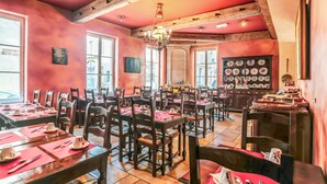 A restaurant with multiple tables and chairs, wooden beams on the ceiling, and a chandelier. - Hôtel du Théâtre (Metz)