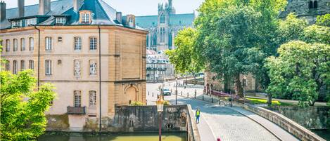 A historic building with a stone facade, a paved walkway, and a body of water in the foreground.