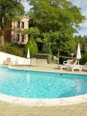 Una piscina al aire libre de temporada, sombrillas