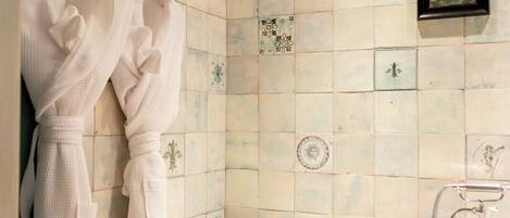 Un baño con una bañera independiente, un perchero con dos albornoces blancos y un cuadro en la pared.