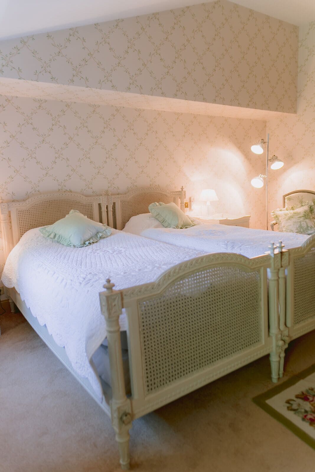 A bedroom with a double bed, two bedside tables, a nightstand, and a lamp.