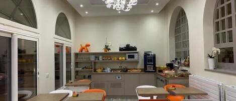 A modern dining area with tables and chairs, a central kitchen area, and a decorative ceiling light.