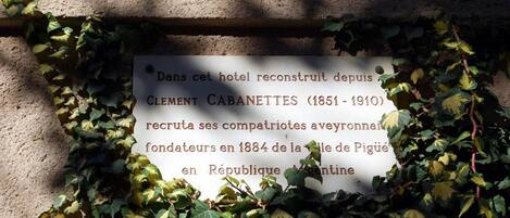 A plaque with historical information about a hotel, surrounded by ivy.