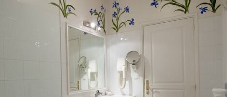A bathroom with white tiles, a bathtub, a sink, a mirror, and a door.