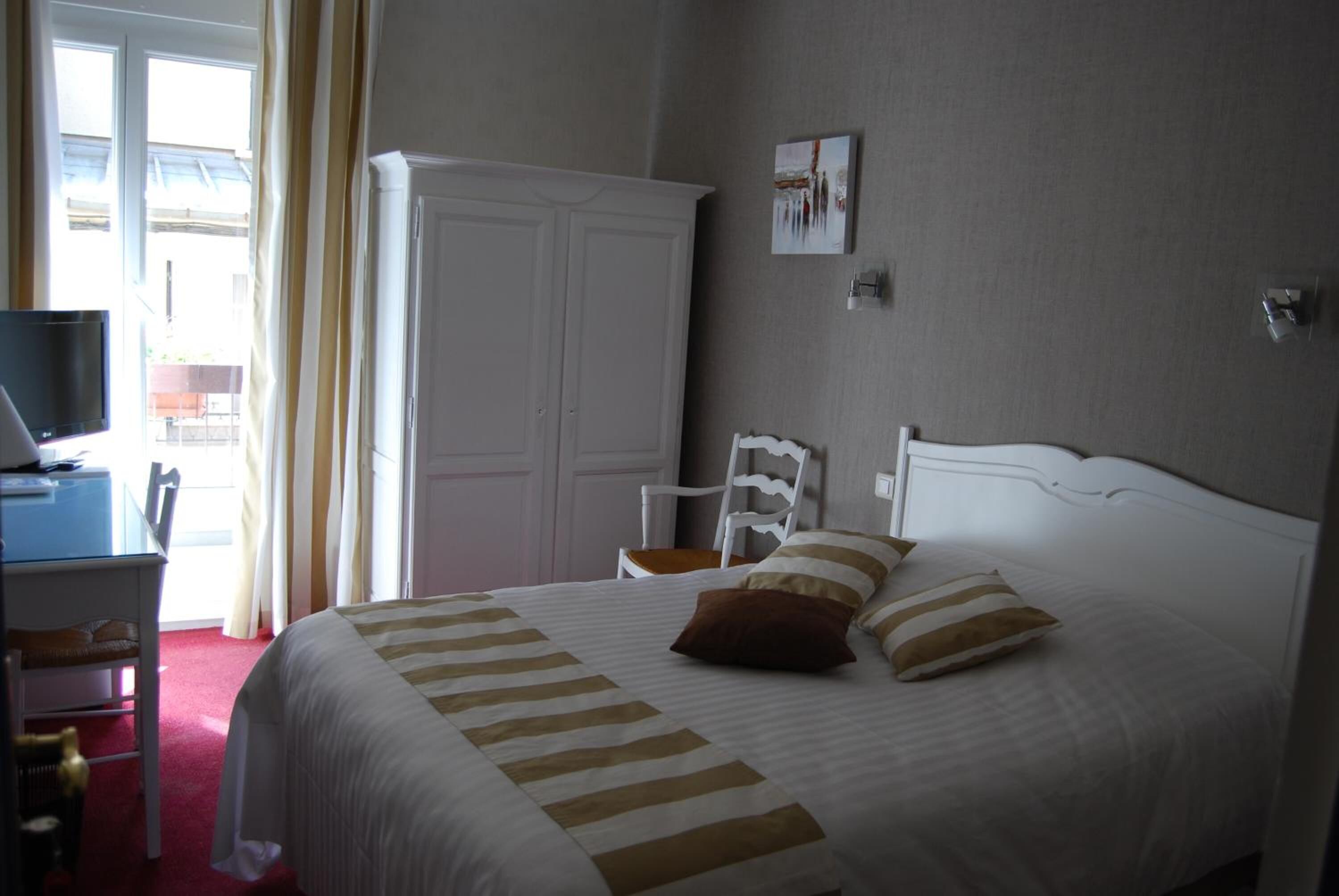 Una habitación de hotel con una cama, un escritorio con una computadora, una silla y un armario.