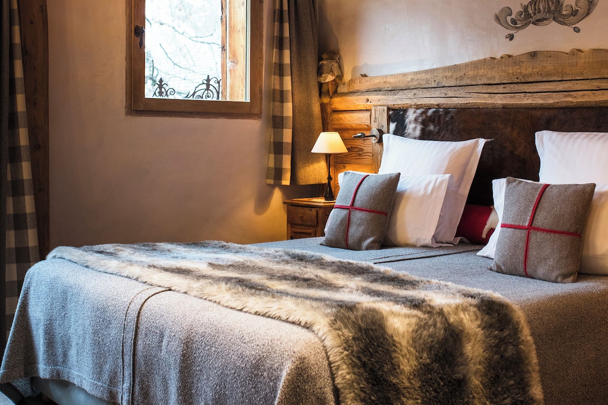 Un plafond en bois rustique avec des poutres apparentes et un lit recouvert d’un plaid en fourrure.