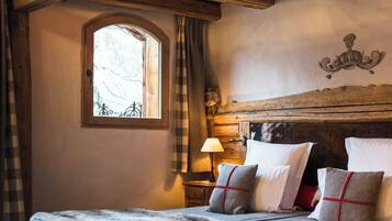 Un plafond en bois rustique avec des poutres apparentes et un lit recouvert d’un plaid en fourrure.