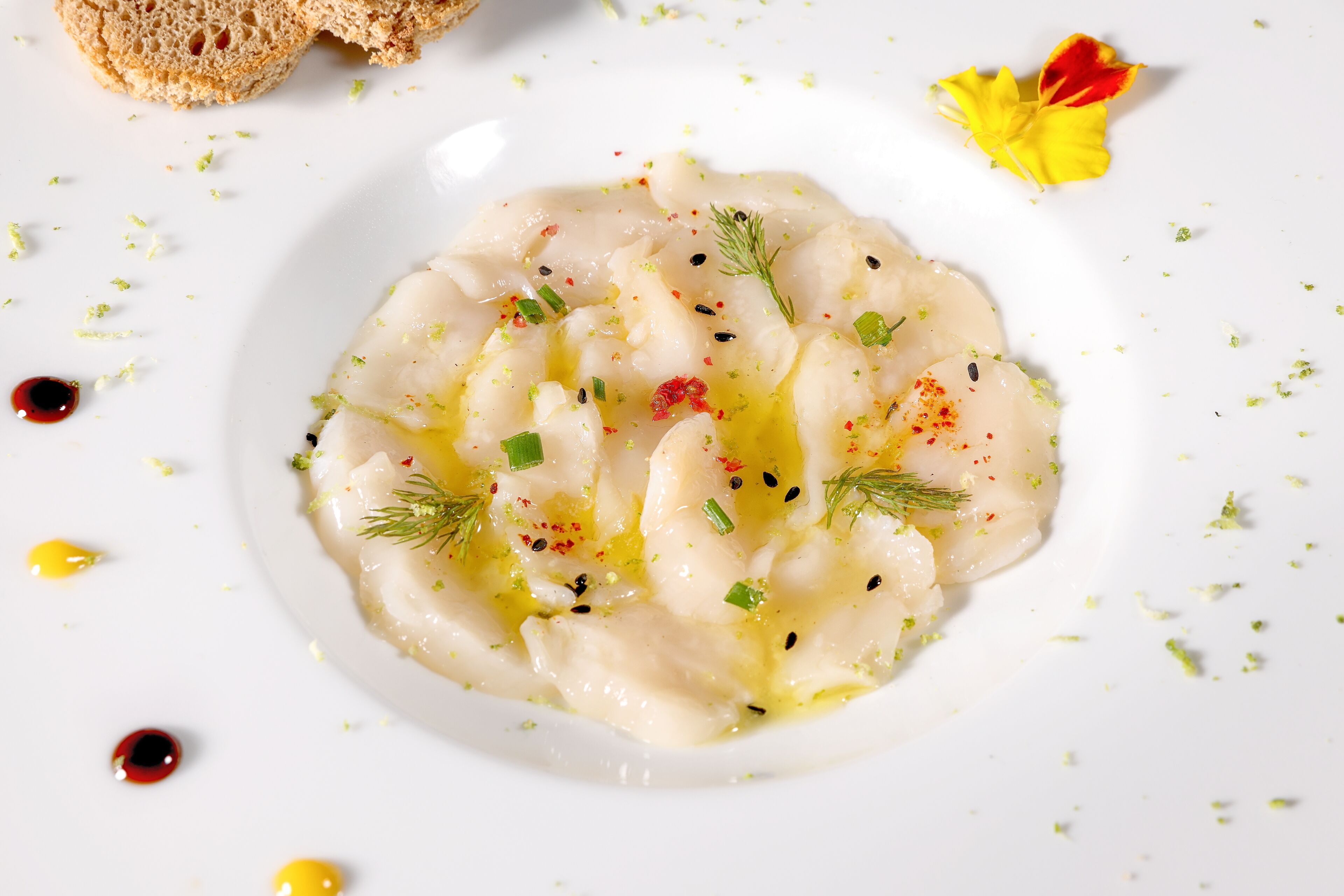 A white plate with a creamy dish garnished with herbs and spices.