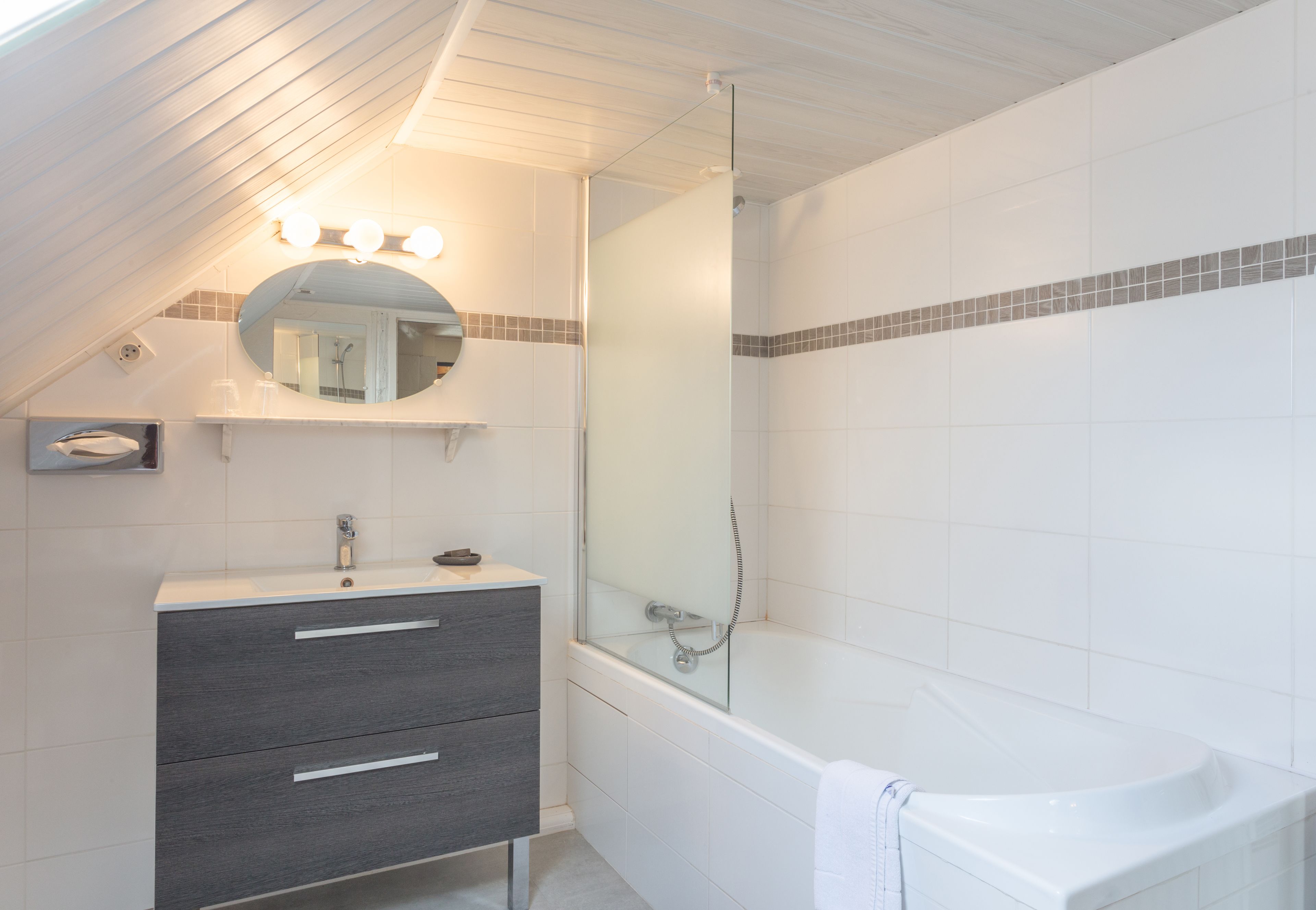 A bathroom with a bathtub, a vanity with drawers, a mirror, and a shower area.