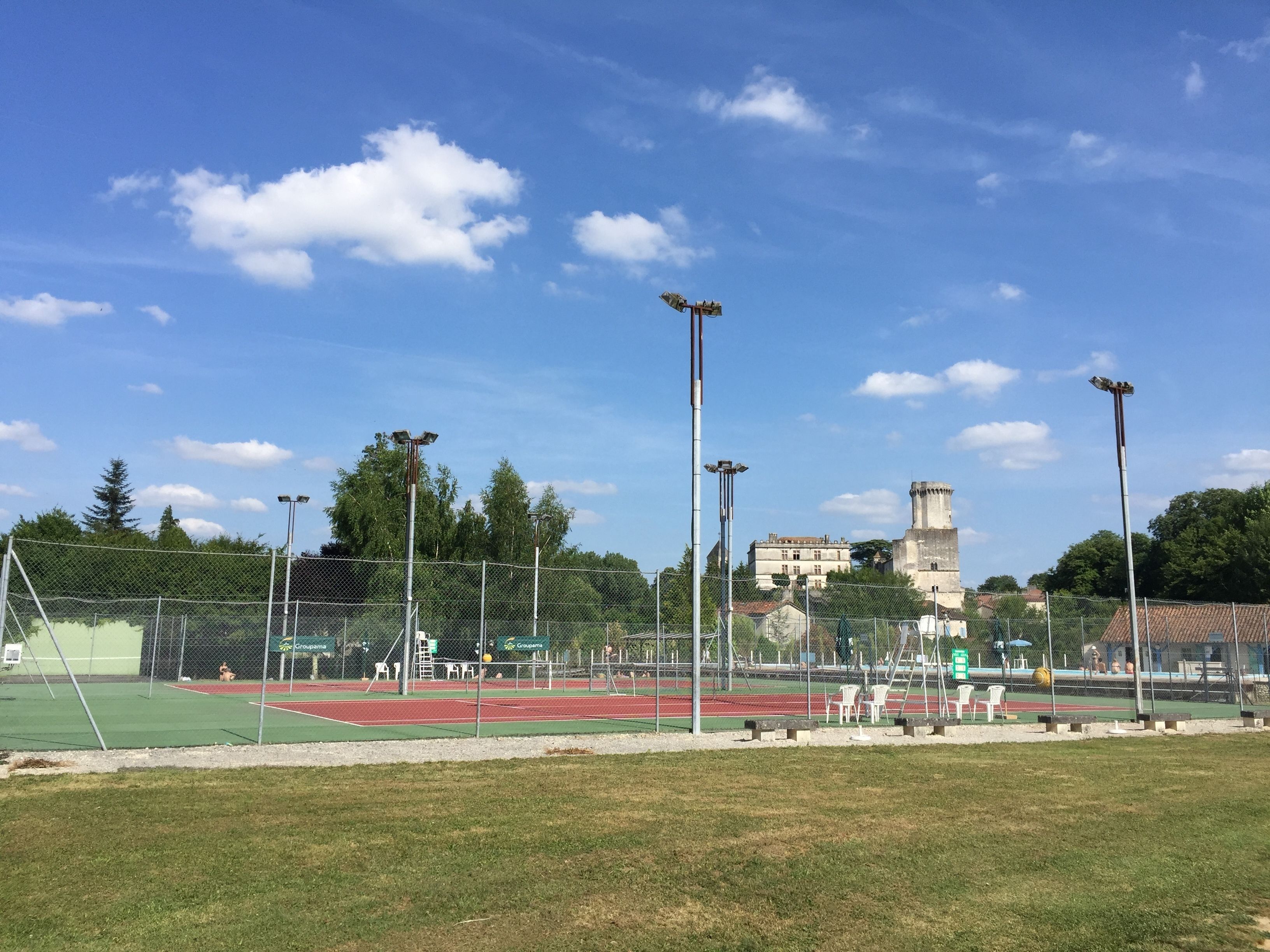 A sports field with a running track, fencing, and a historic building in the background.